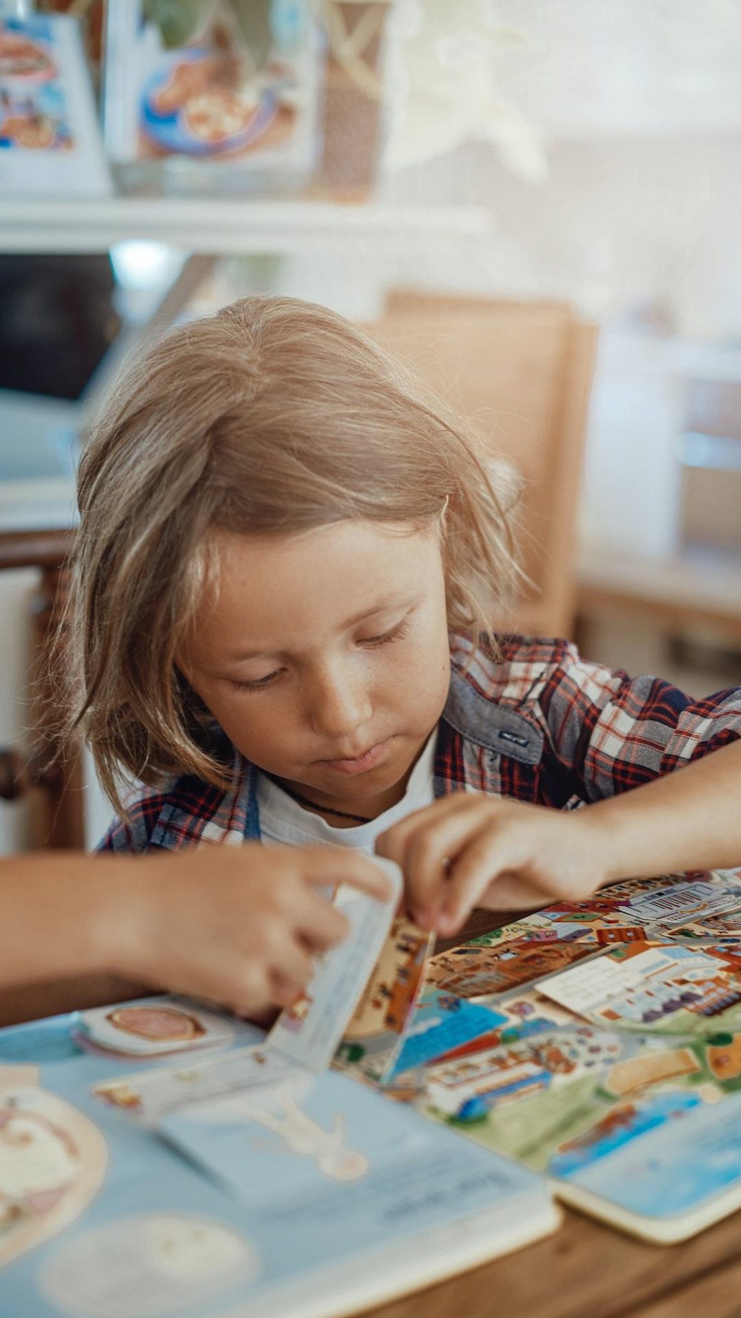 Cheerful kid reads a book at table in lovely and modern living room